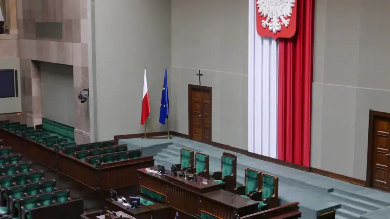 Sala posiedzeń polskiego Sejmu z godłem państwowym i ławami poselskimi w tle