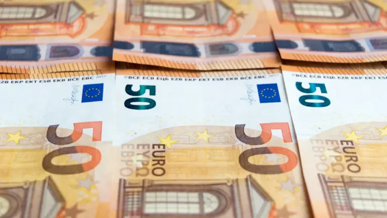 Banknoty pięćdziesięcioeuro ułożone w rzędach na drewnianym stole jako symbol europejskiej waluty.