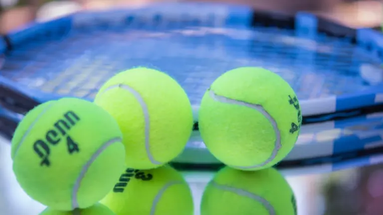 Profesjonalna rakieta tenisowa oraz piłki na niebieskim korcie przed finałem US Open.