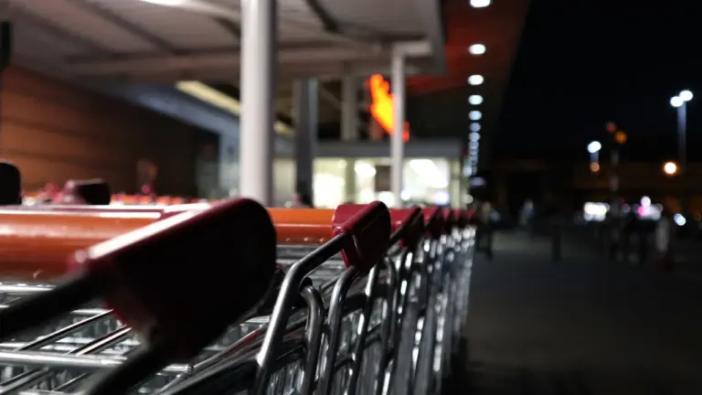 Rząd wózków sklepowych przy wejściu do marketu w czasie niedzieli handlowej wieczorem