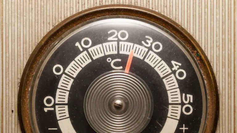 Zbliżenie na okrągły termometr ścienny wskazujący wysokie temperatury w letni dzień.