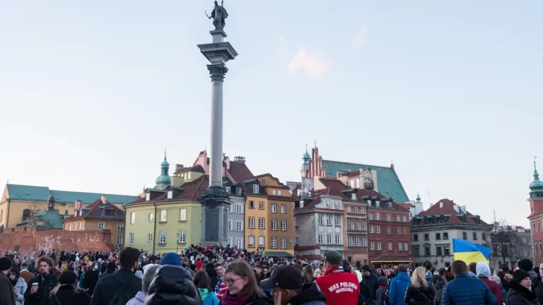Tłum ludzi na Placu Zamkowym w Warszawie pod Kolumną Zygmunta w słoneczny dzień.