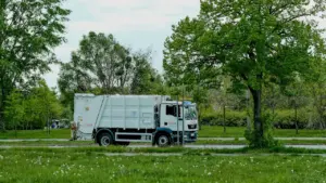 Śmieciarka jadąca przez zieloną okolicę, przygotowana do codziennej pracy w mieście.