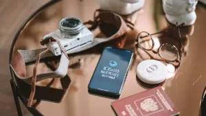 Przedmioty podróżne: aparat, telefon, okulary i paszport na szklanym stoliku przed wyjazdem.