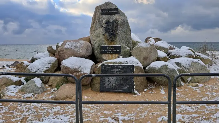 Pomnik upamiętniający obronę Westerplatte w otoczeniu zimowej scenerii nad morzem.