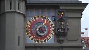 Zabytkowy zegar astronomiczny z widocznymi symbolami znaków zodiaku na elewacji budynku.